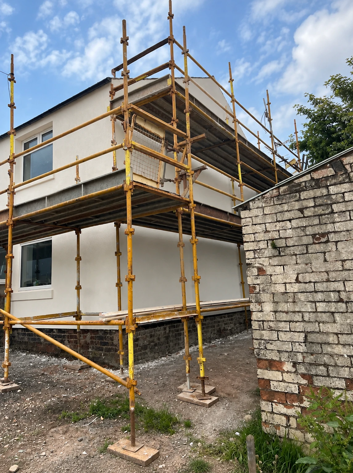Off-white render being applied under scaffold